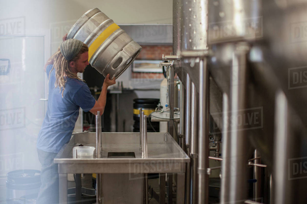 Man filling beer keg in microbrewery Stock Photo Dissolve
