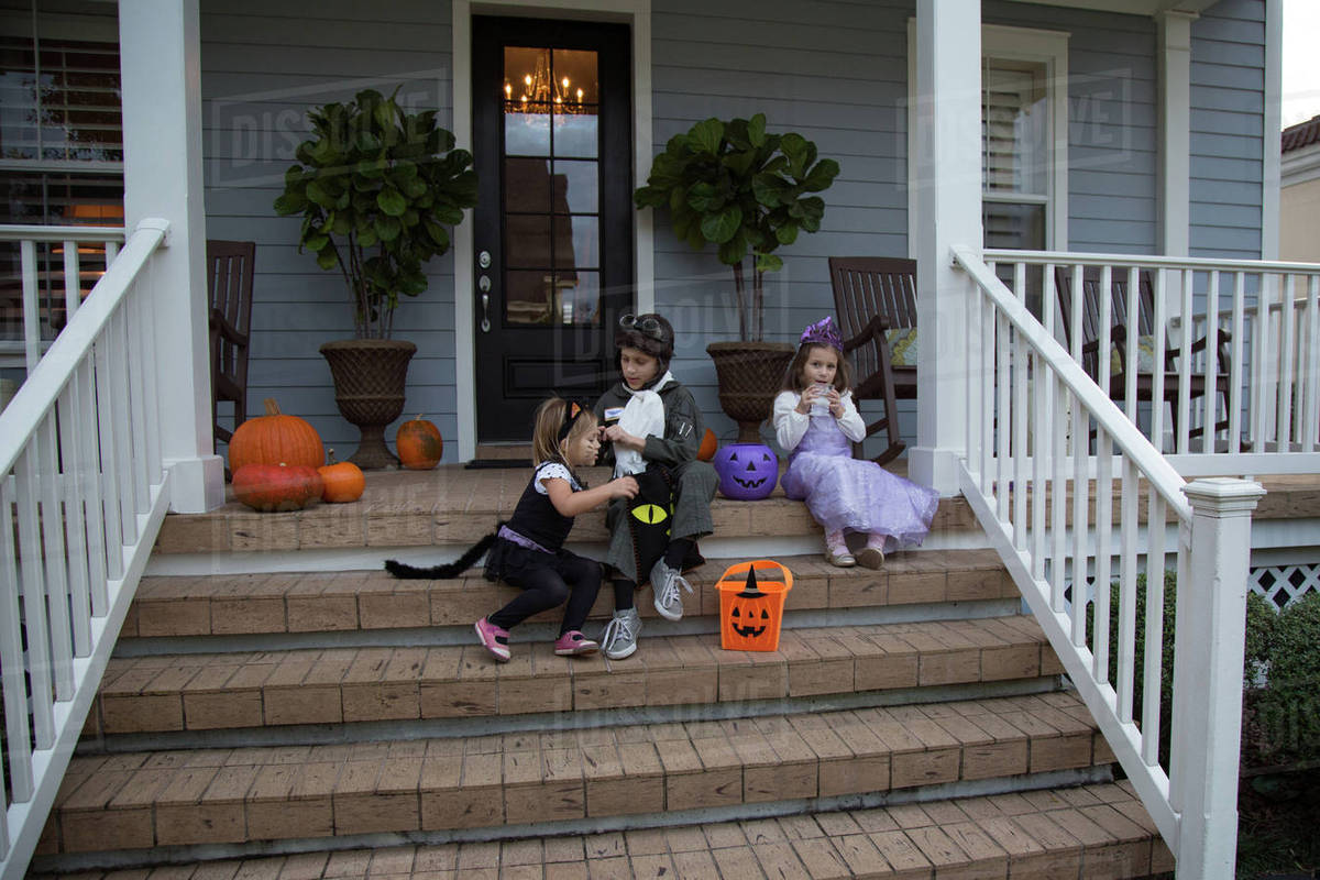 Brother and sisters trick or treating on porch stairway Royalty-free stock photo