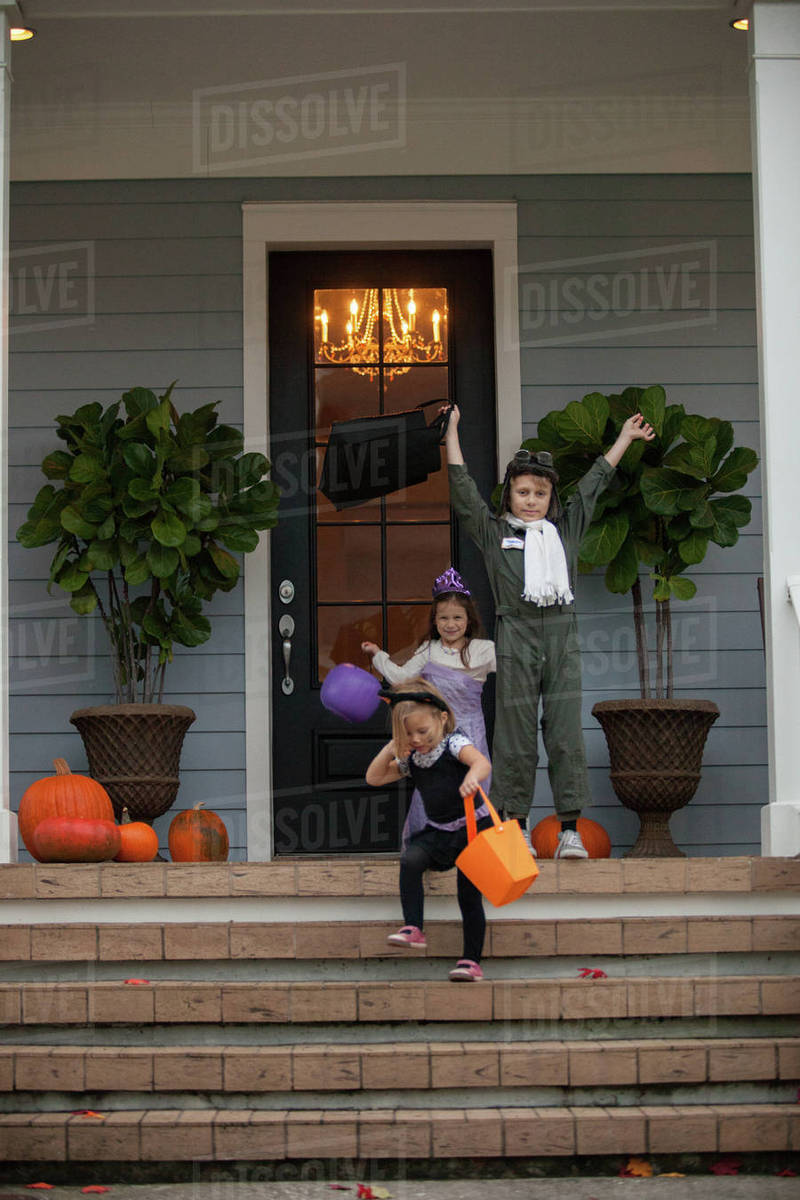 Boy and sisters trick or treating celebrating on porch Royalty-free stock photo