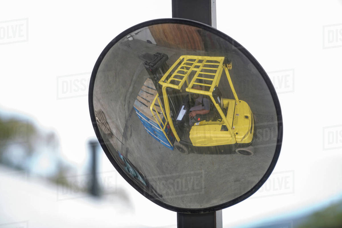 Convex mirror image of forklift driver at packaging factory Stock