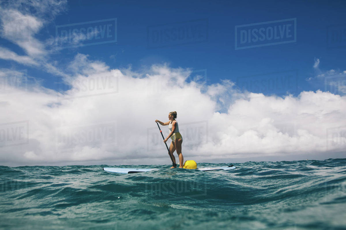 Pregnant mid adult woman stand up paddleboarding in sea, Makua beach