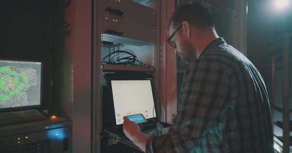 Young male programmer downloads data on smartphone while working on ...