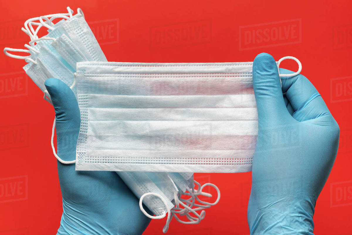 Doctor holds lot respiratory surgical face mask in hands blue medical