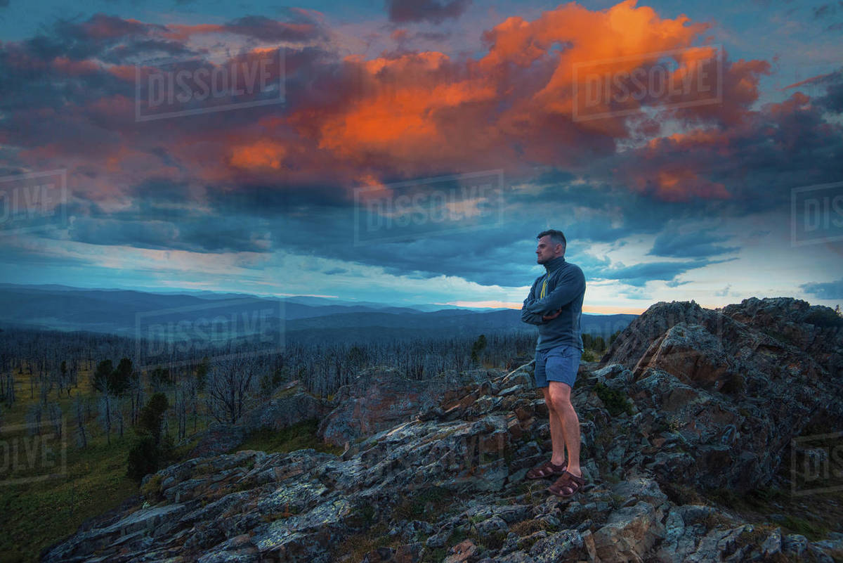 Travel, freedom and tourism concept - man standing on top of cliff in summer beauty evening in Altai mountains, fantastic sunset Royalty-free stock photo