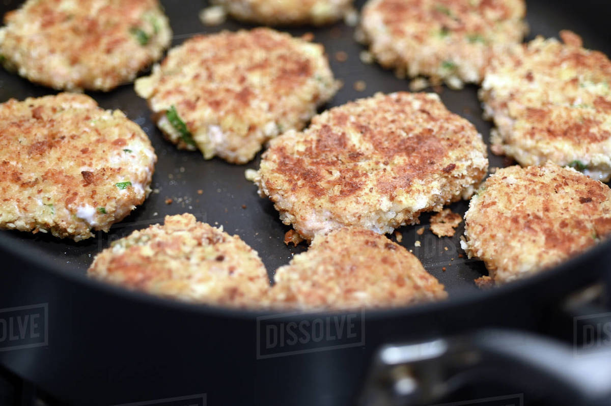 Fish cake coated with breadcrumbs cooking in a fry pan. Stock Photo Dissolve