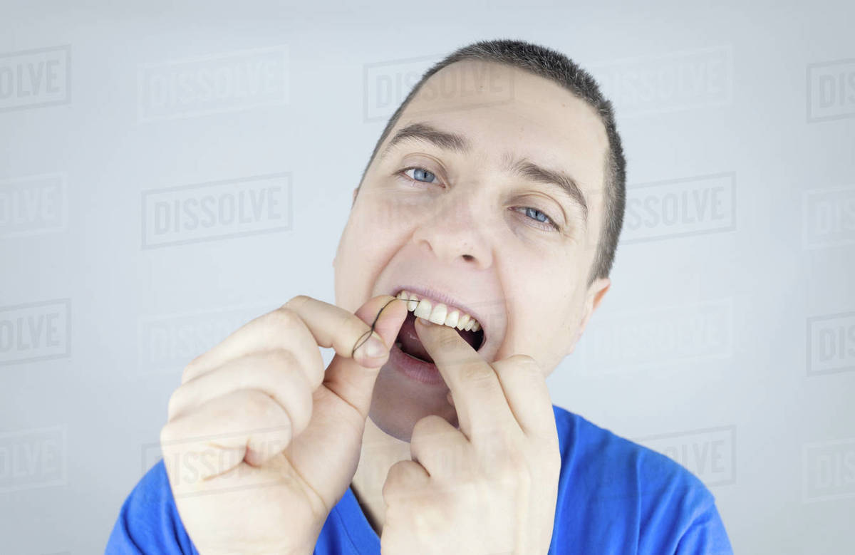 Dental floss close up. A man in front of a mirror brushes his teeth