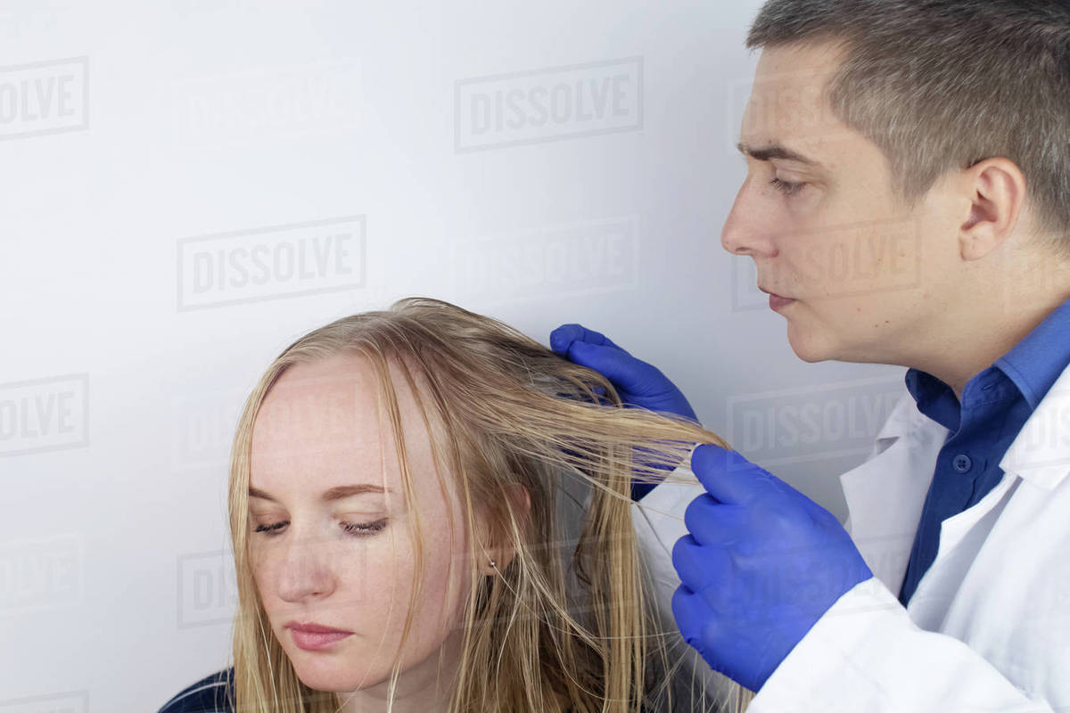 A trichologist examines a girl with oily hair. Problematic scalp and increased secretion of the