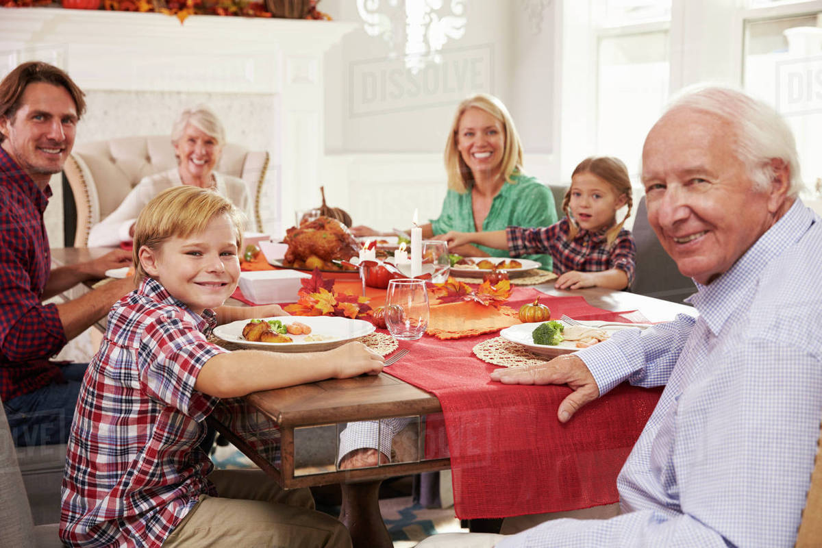 Family with grandparents enjoying thanksgiving meal at table Stock