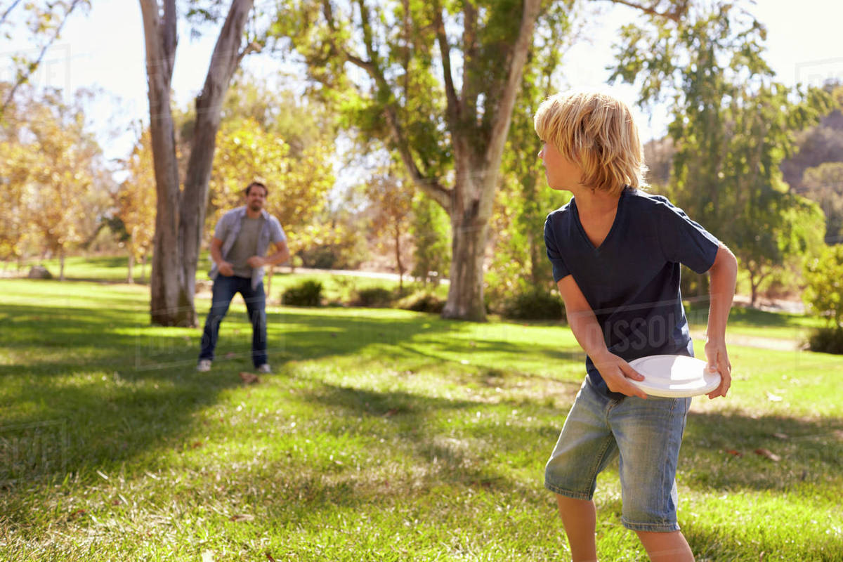 Father and son throwing frisbee in park together Stock Photo Dissolve