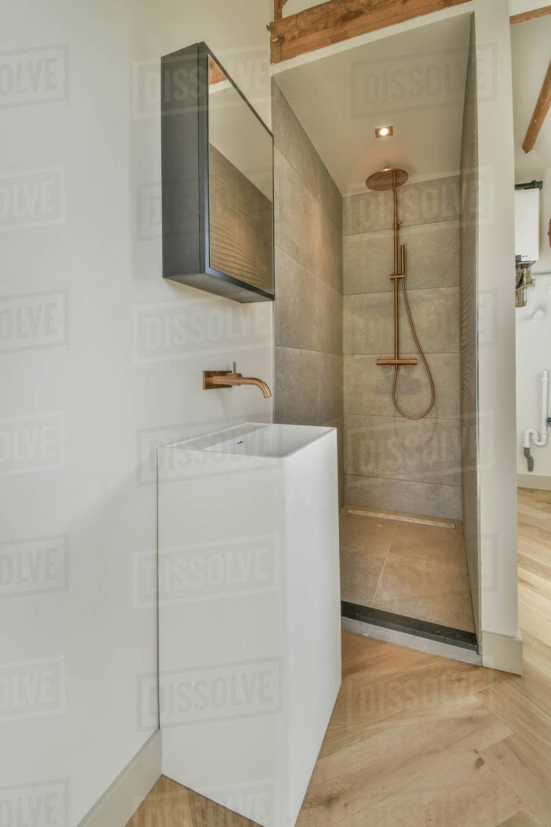 Stylish wash basin with large round mirror and walkin shower nearby