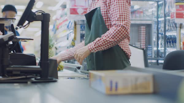 At the supermarket: checkout counter hands of the cashier scans ...