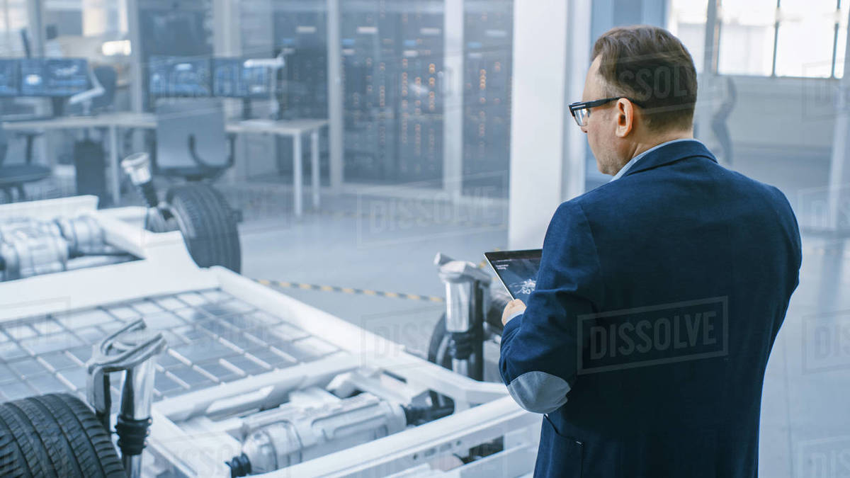 Automotive Design Engineer Looking at Technical Drawing of an Electric