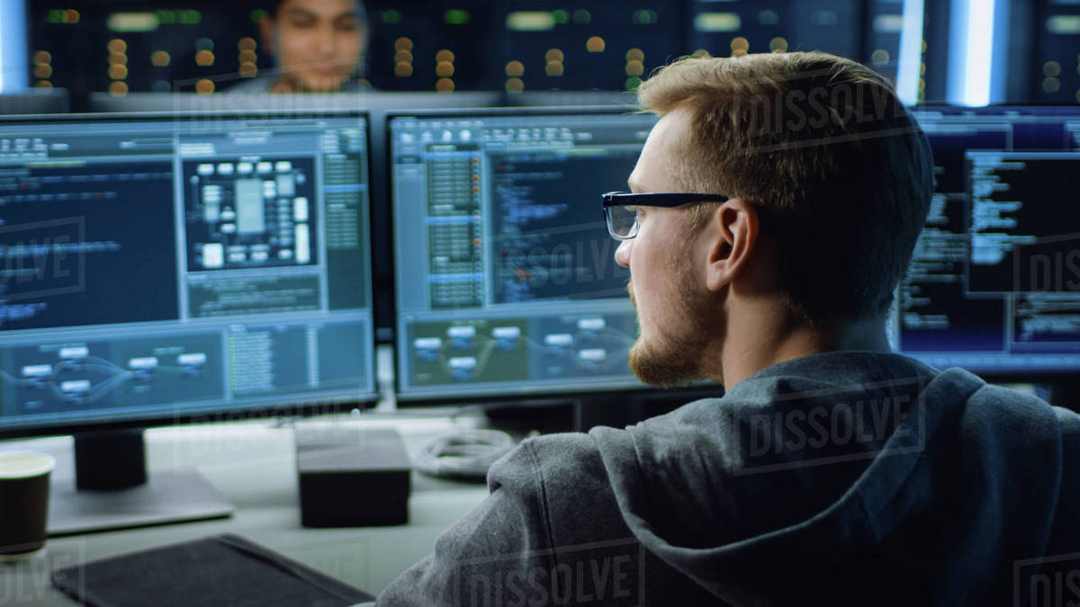 IT Specialist Working on Personal Computer with Monitors Showing Coding