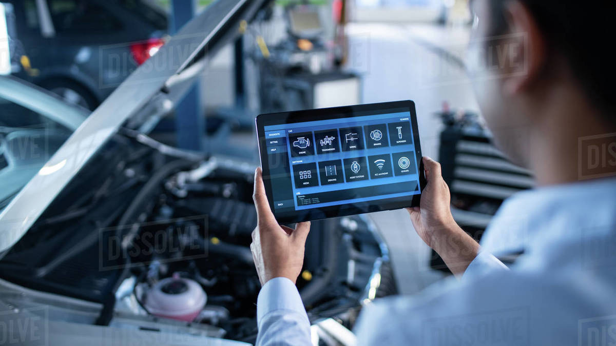 Car Service Manager or Mechanic Uses a Tablet Computer with a Futuristic Interactive Diagnostics Software. Specialist Inspecting the Vehicle in Order to Find Broken Components In the Engine Bay. Royalty-free stock photo