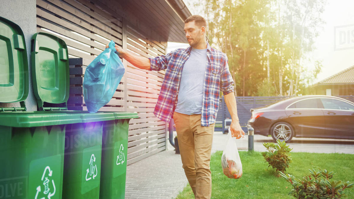 Man throwing away trash next to his house Stock Photo Dissolve