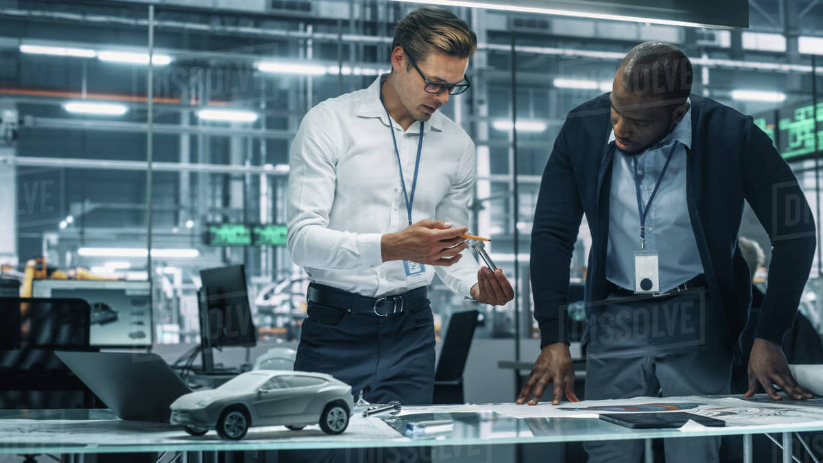 Two Automotive Engineers Working in Office at Car Factory Stock Photo
