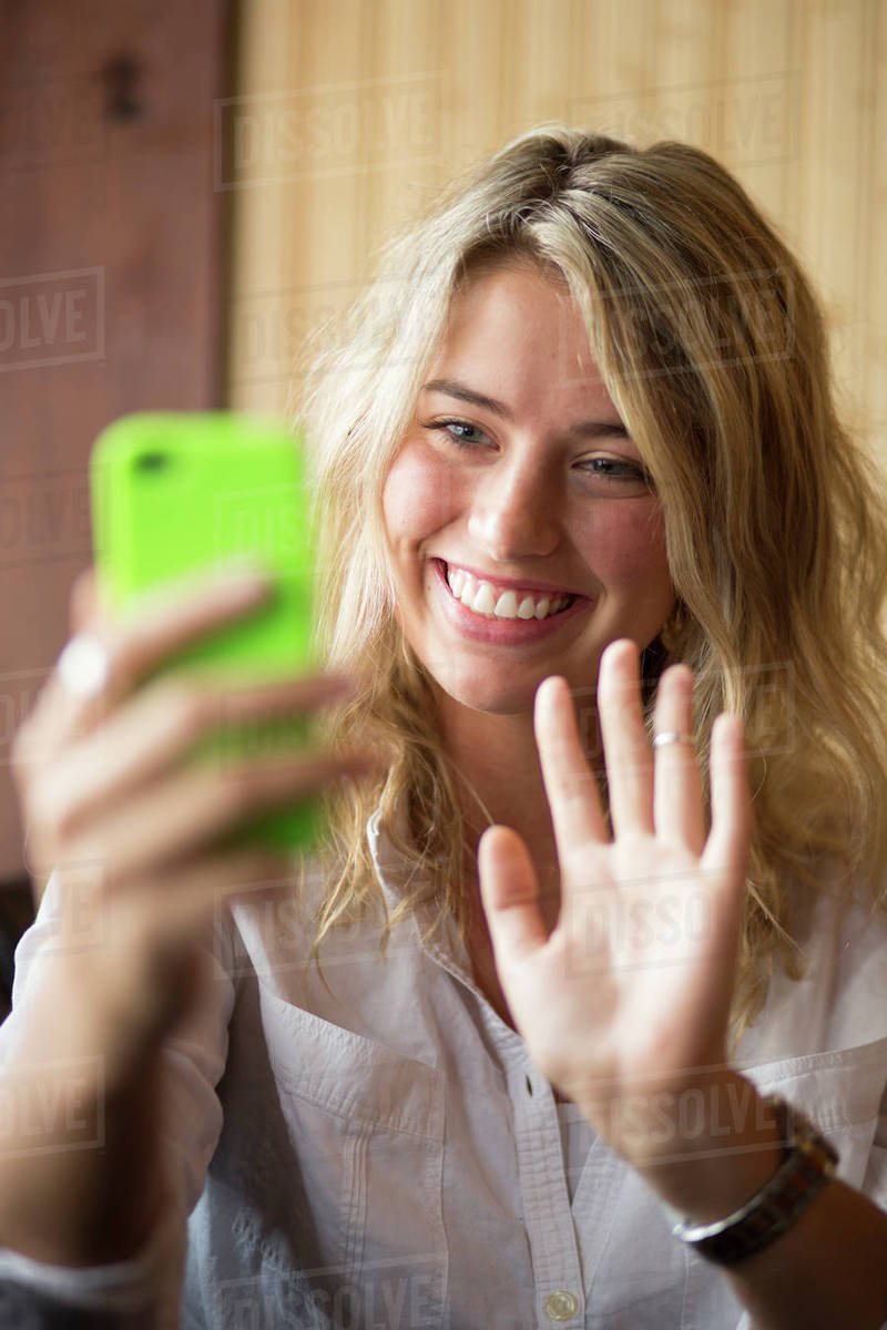 Selective focus close up of happy woman waving at cell phone and video chatting Royalty-free stock photo