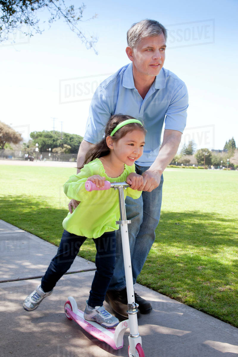 Father Helping His Daughter Ride A Scooter Menlo Park California Father Helping His Daughter Ride A Scooter Menlo Park California United States Of America