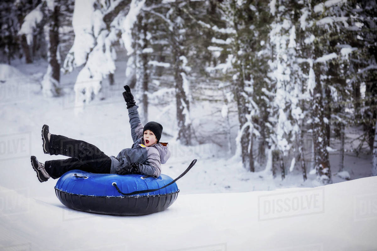 Young boy tubing down a ski hill; Fairmont Hot Springs, British Columbia, Canada Stock Photo