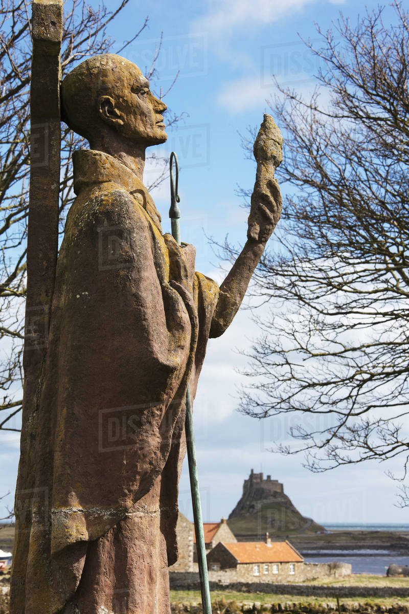 A statue of an historic figure standing against a cross and a view of