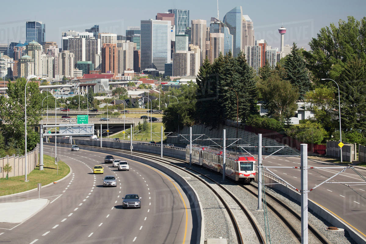 Skyline of downtown Calgary with roadway and light rail train; Beiseker