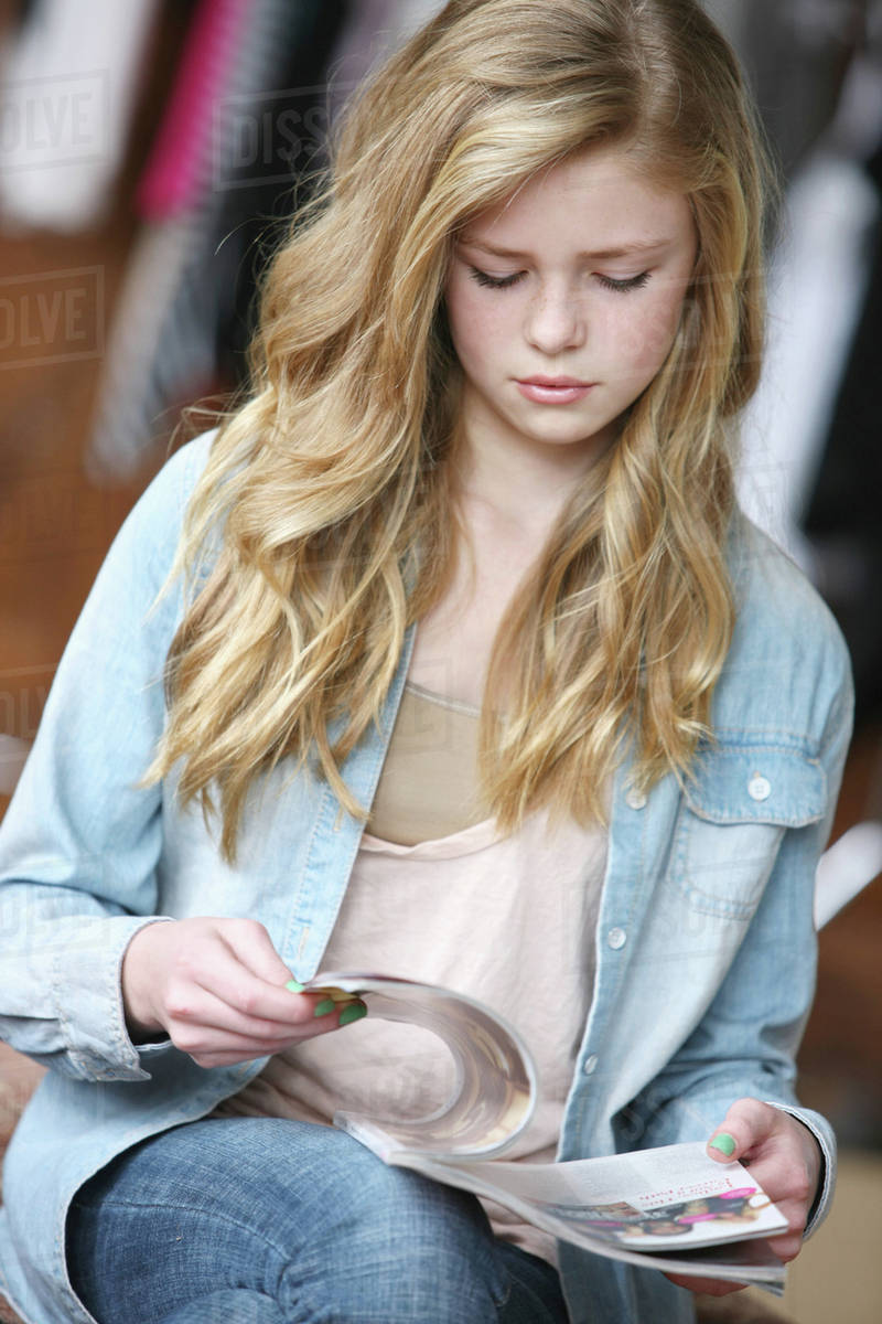 Teenage Girl With Long Blond Hair And Blue Eyes Reading A Magazine