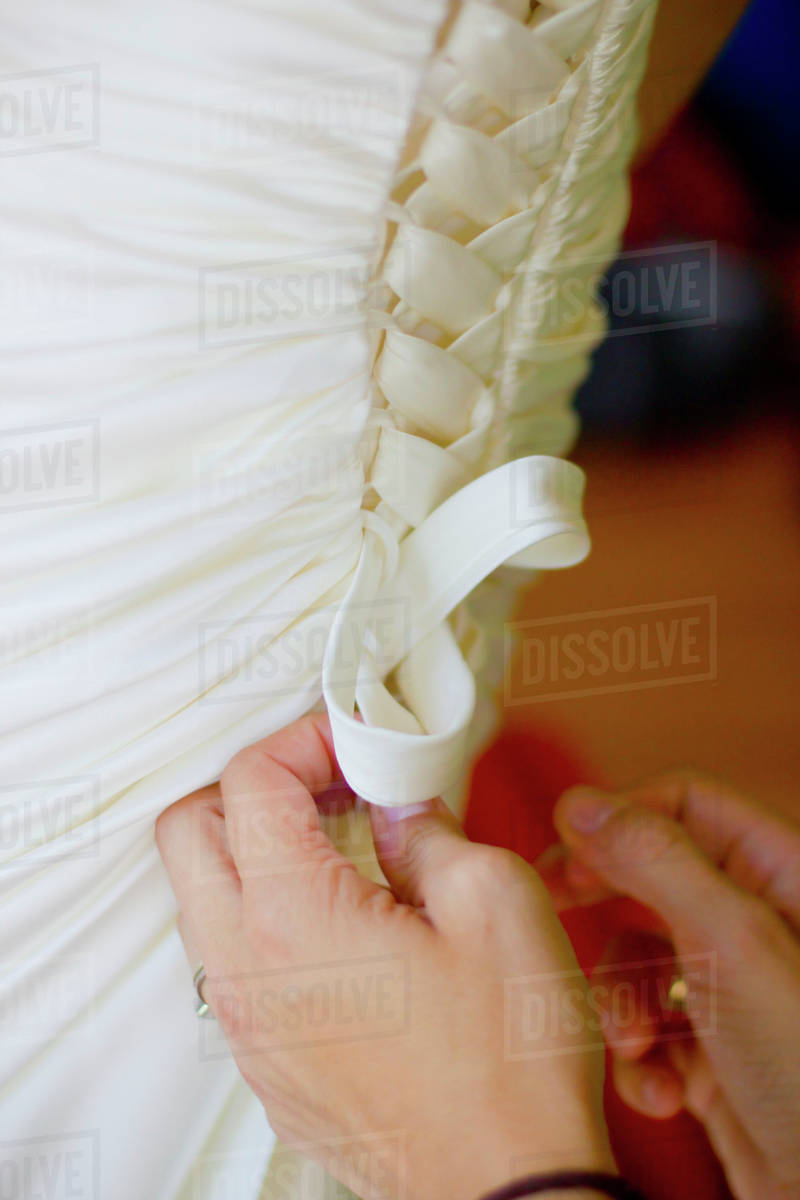 Hands Fastening The Laces On The Back Of A Bride's Gown; Vancouver