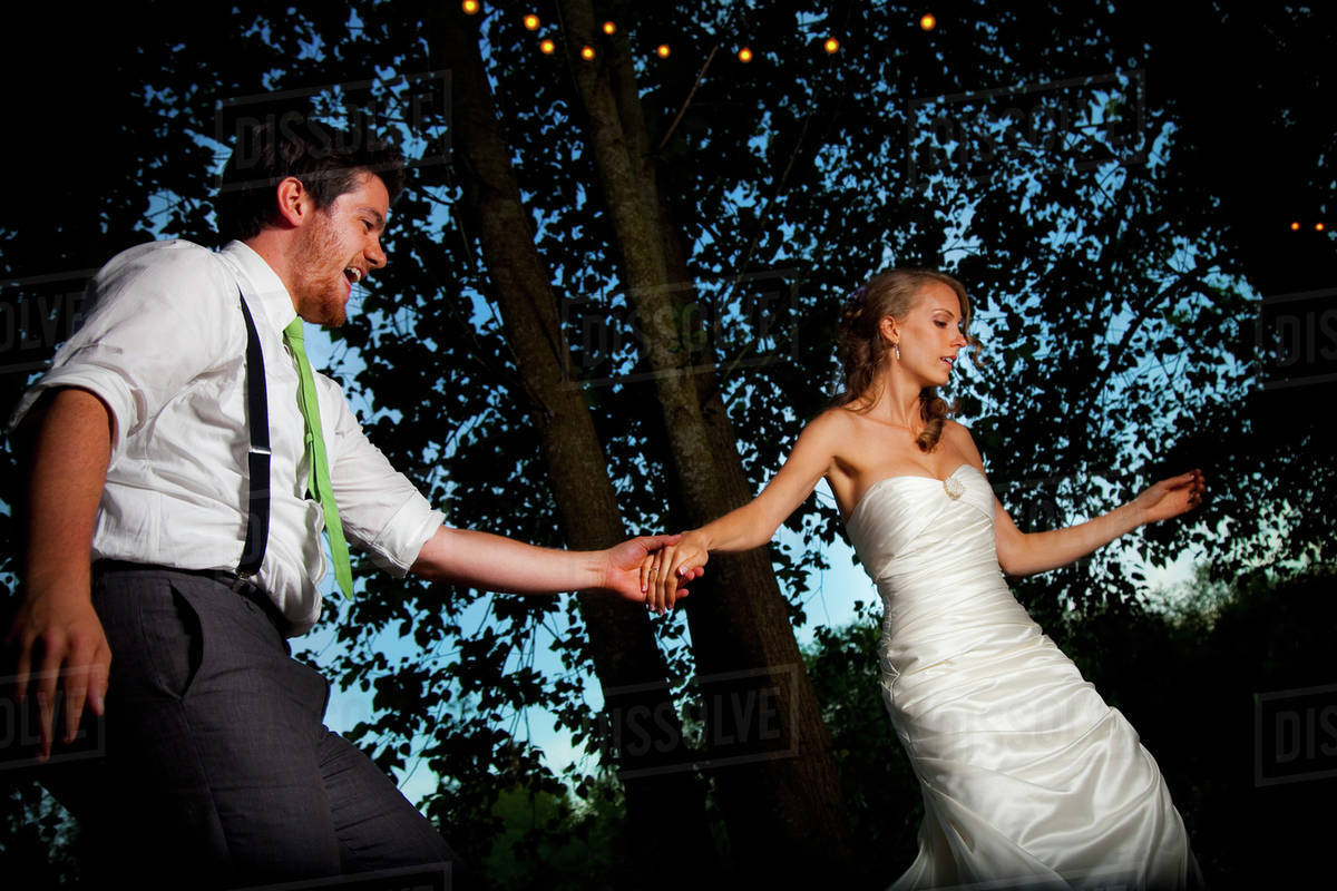A Bride And Groom Dancing At Dusk On An Illuminated Dance Floor