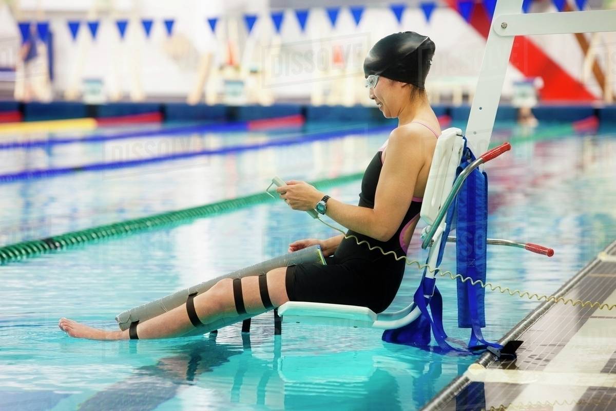 A Paraplegic Woman Is Lowered Into The Swimming Pool On A Lift And