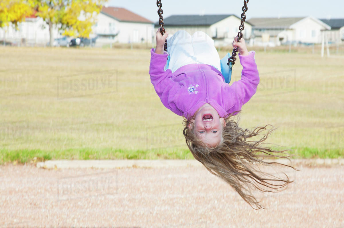 Young girl on swing in a playground in residential community on a
