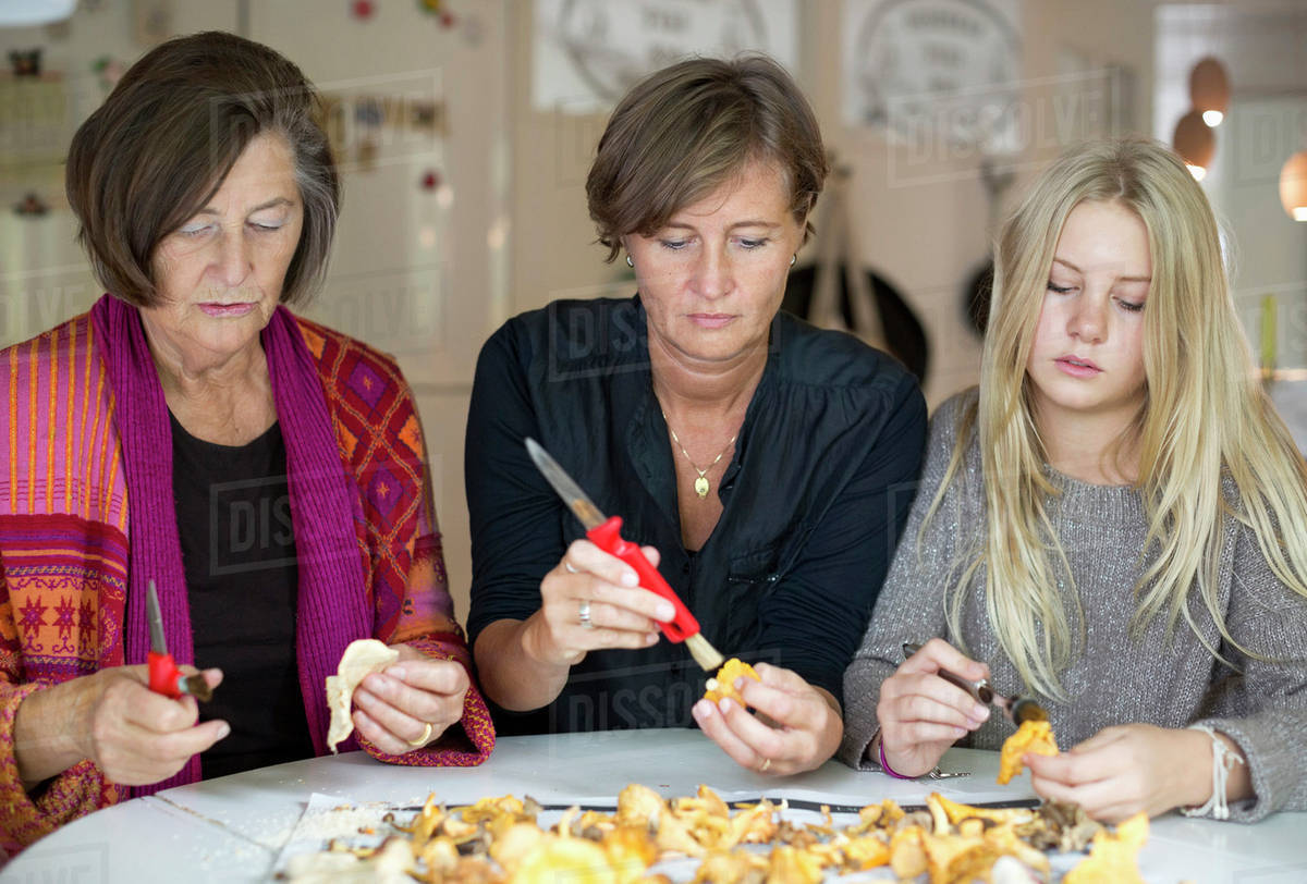 Three generation females cleaning chanterelle mushroom at home Stock
