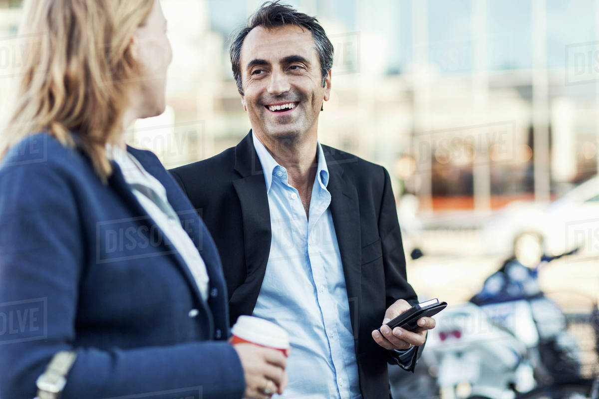 Happy businessman talking to female colleague outdoors Royalty-free stock photo