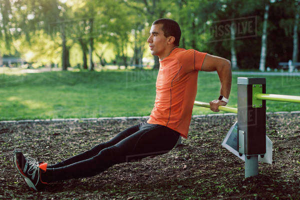 Man doing push-ups on railing at park - Stock Photo - Dissolve