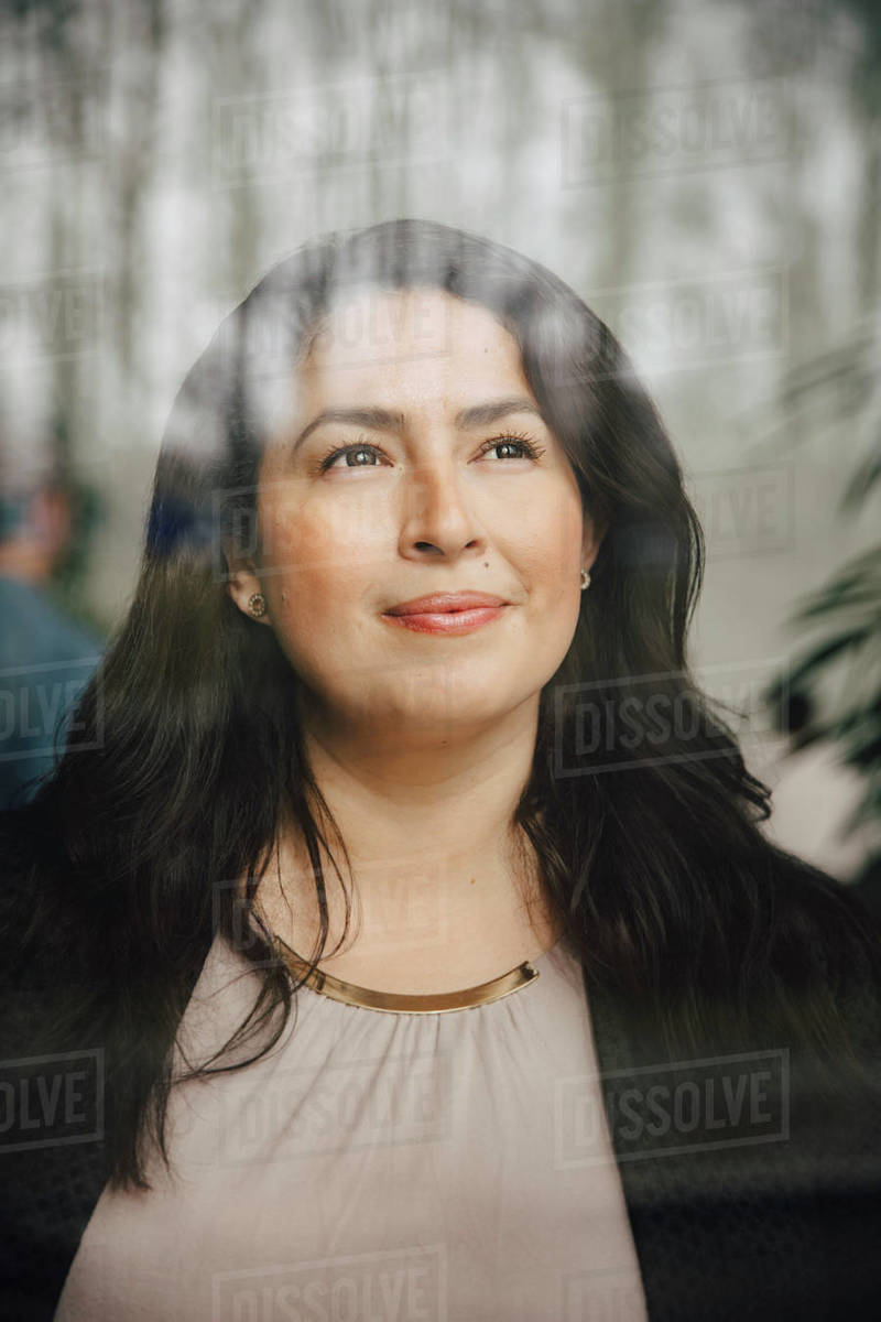 Thoughtful female entrepreneur looking through window while standing at office Royalty-free stock photo