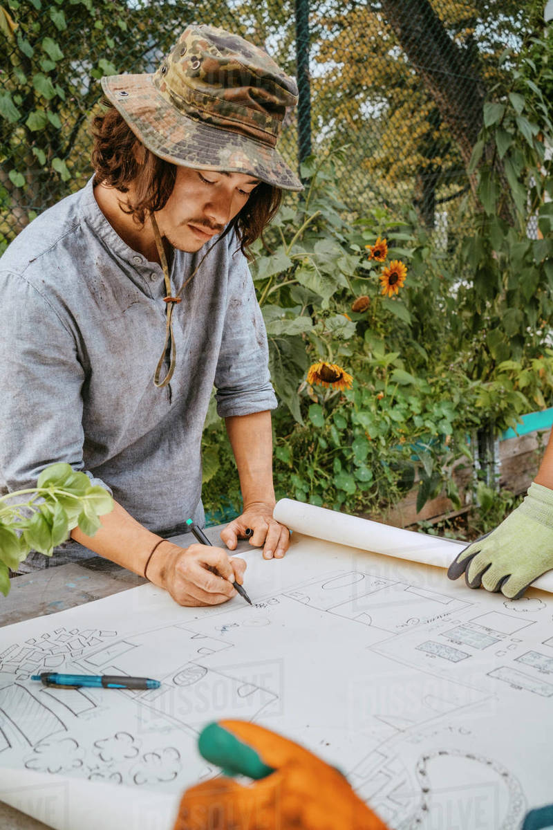 Male environmentalist drawing on blueprint at table Royalty free