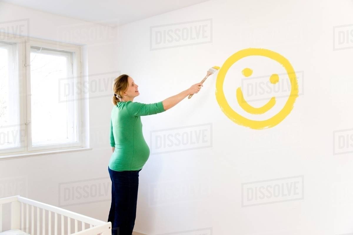 Pregnant woman painting nursery Stock Photo Dissolve