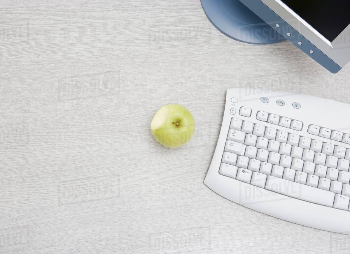 Apple on desk by pc Stock Photo Dissolve