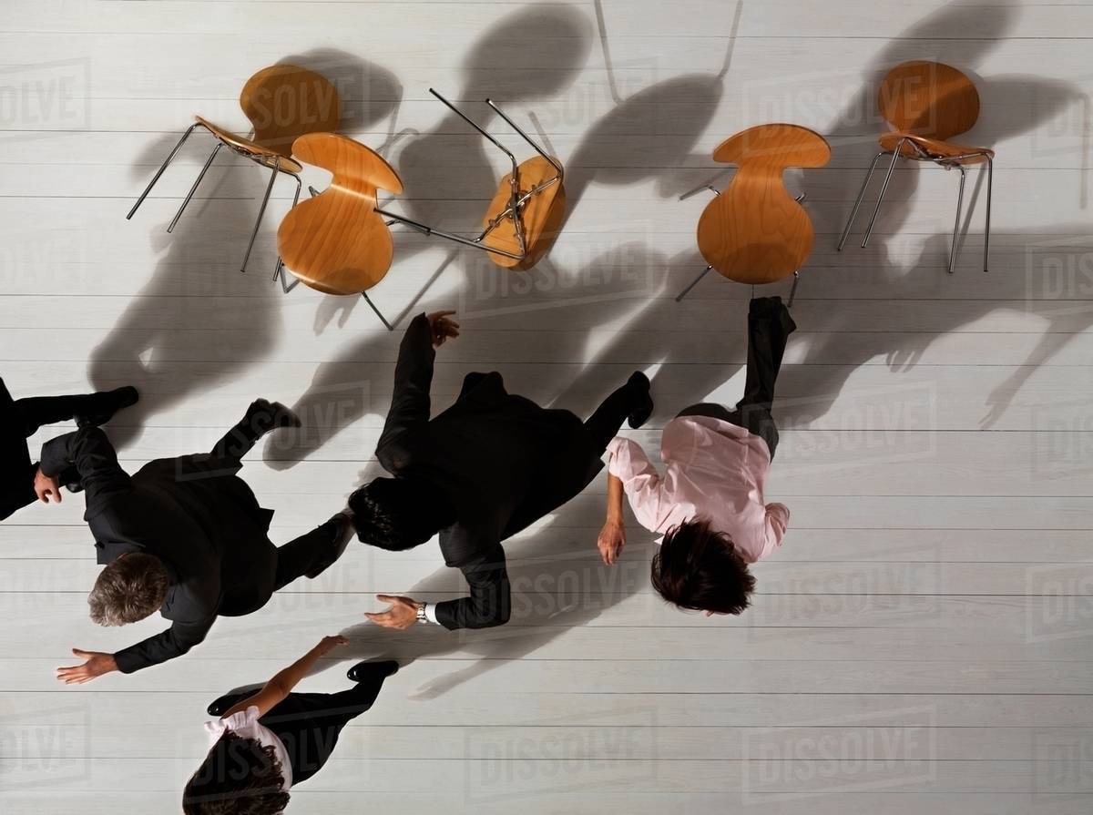 Business people knocking over chairs Stock Photo Dissolve