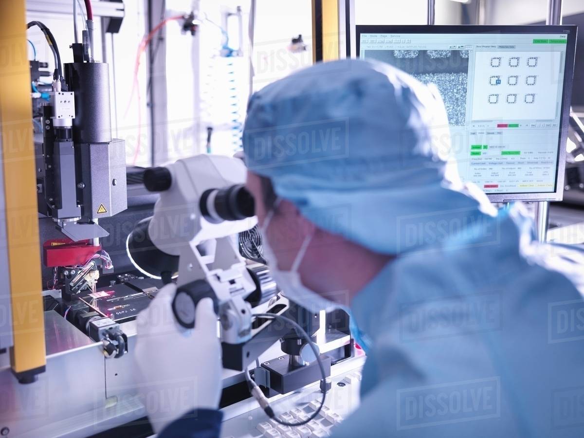 Electronics worker checking component in clean room Stock Photo