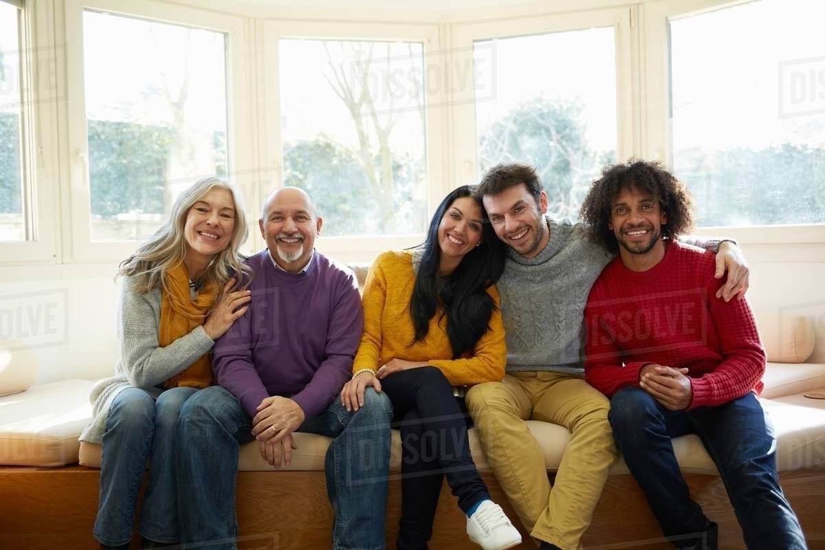 Family side by side on window seat looking at camera smiling Stock