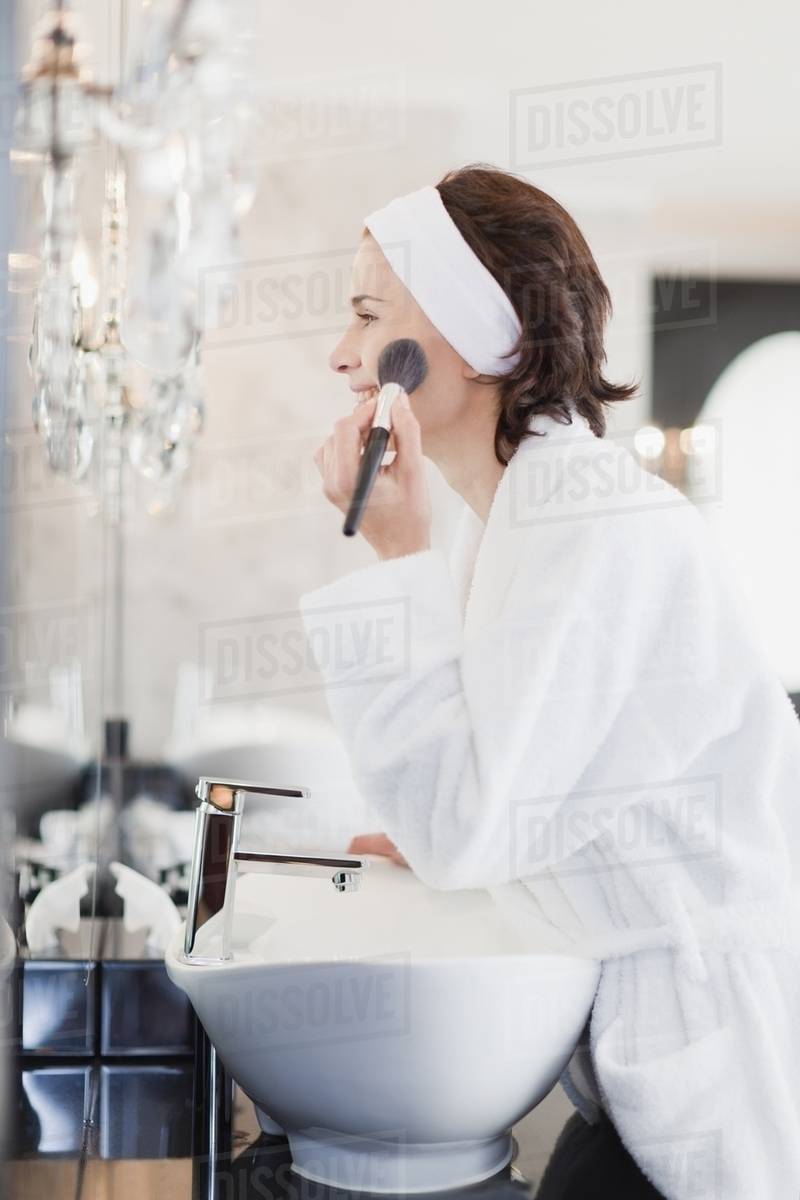 Woman in bathrobe applying makeup Stock Photo Dissolve