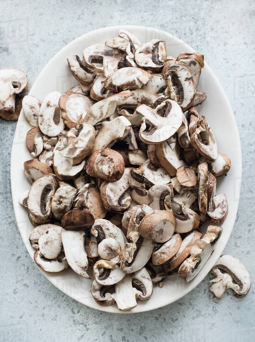 Overhead view of fresh sliced mushrooms on a plate Stock Photo Dissolve