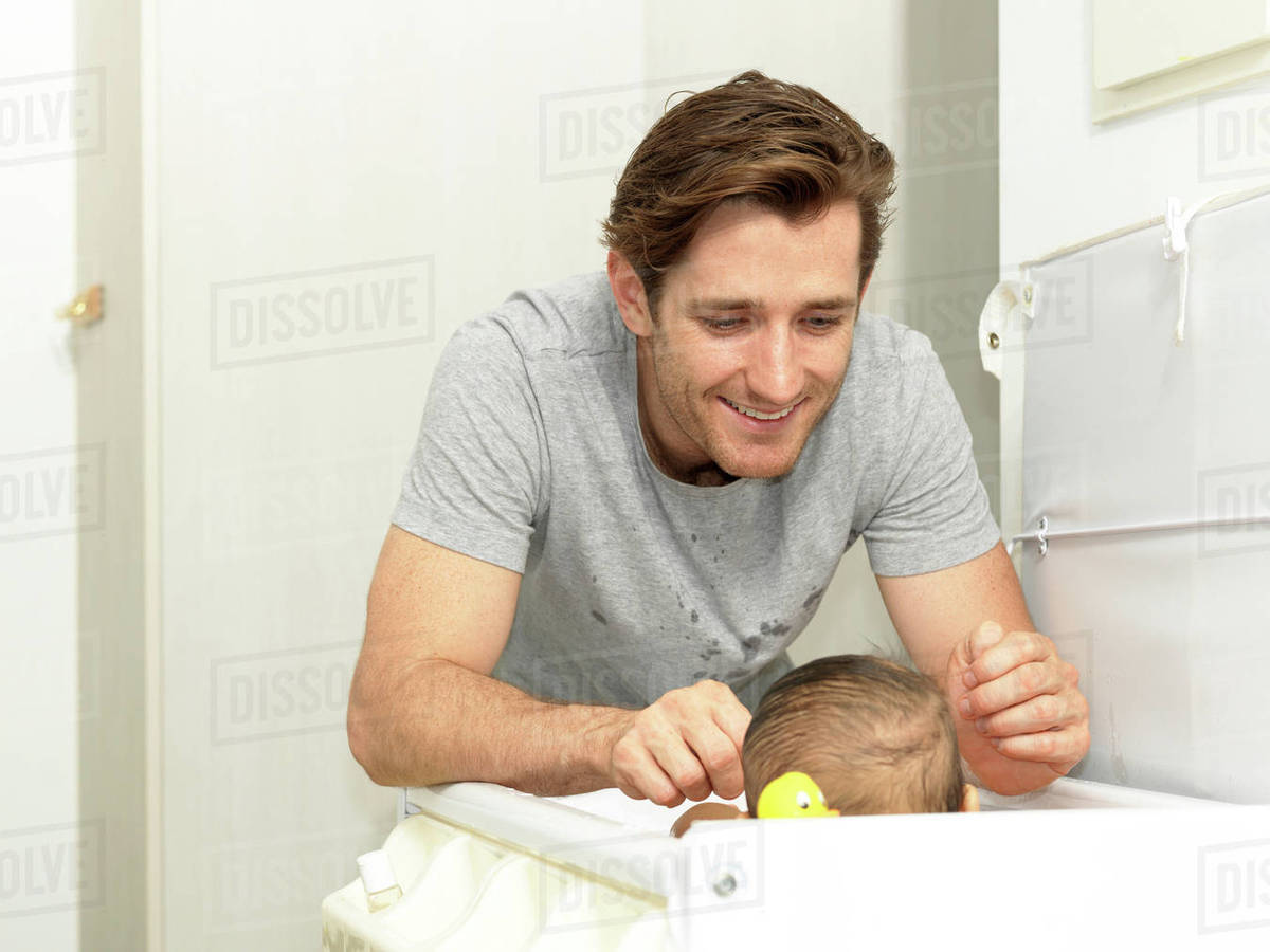 Smiling father changing baby boys nappy Stock Photo Dissolve