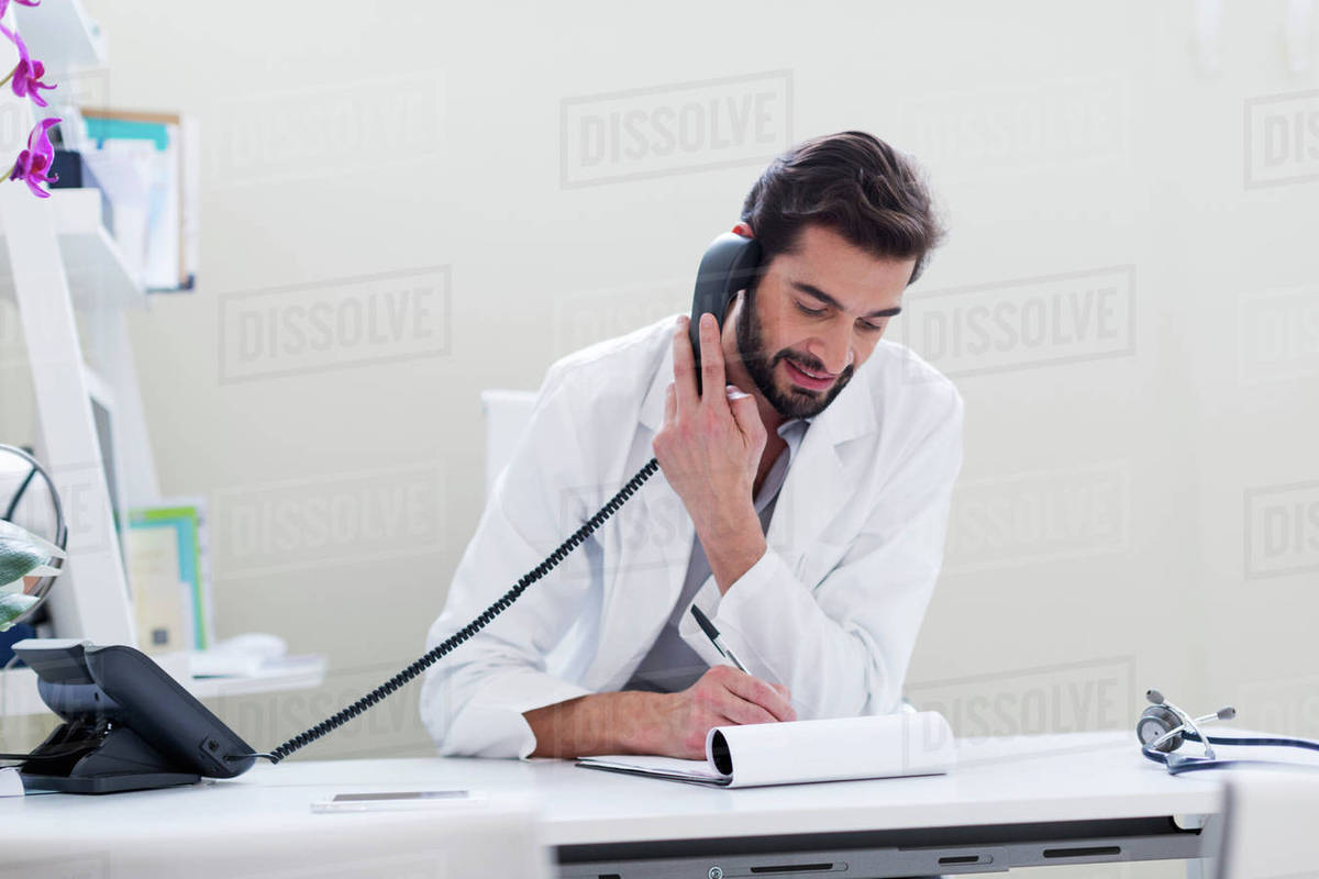 Doctor at desk making telephone call Stock Photo Dissolve