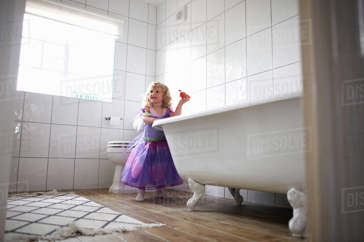 Young girl dressed in fairy costume, standing beside bathtub Royalty-free stock photo