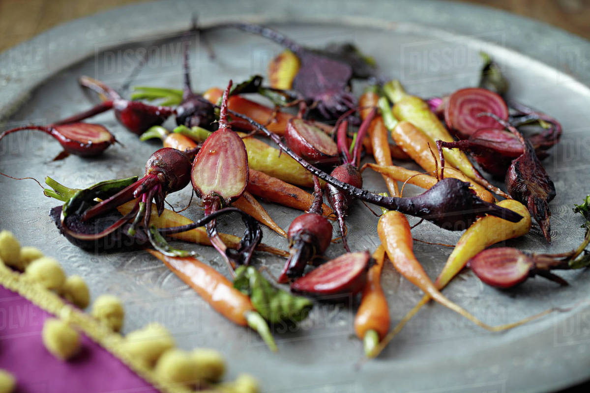 Roasted baby vegetables on tray Stock Photo Dissolve