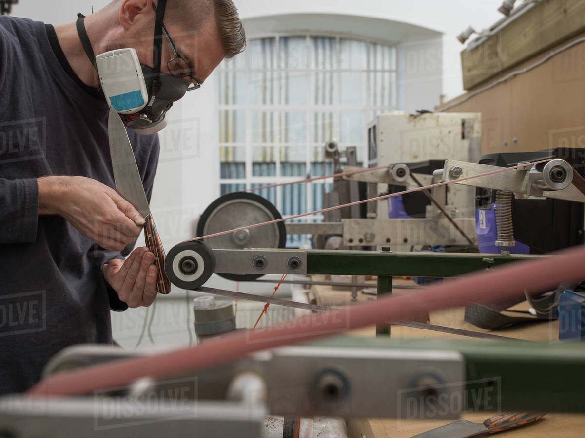 Knife factory worker sanding knife handle in Stock Photo