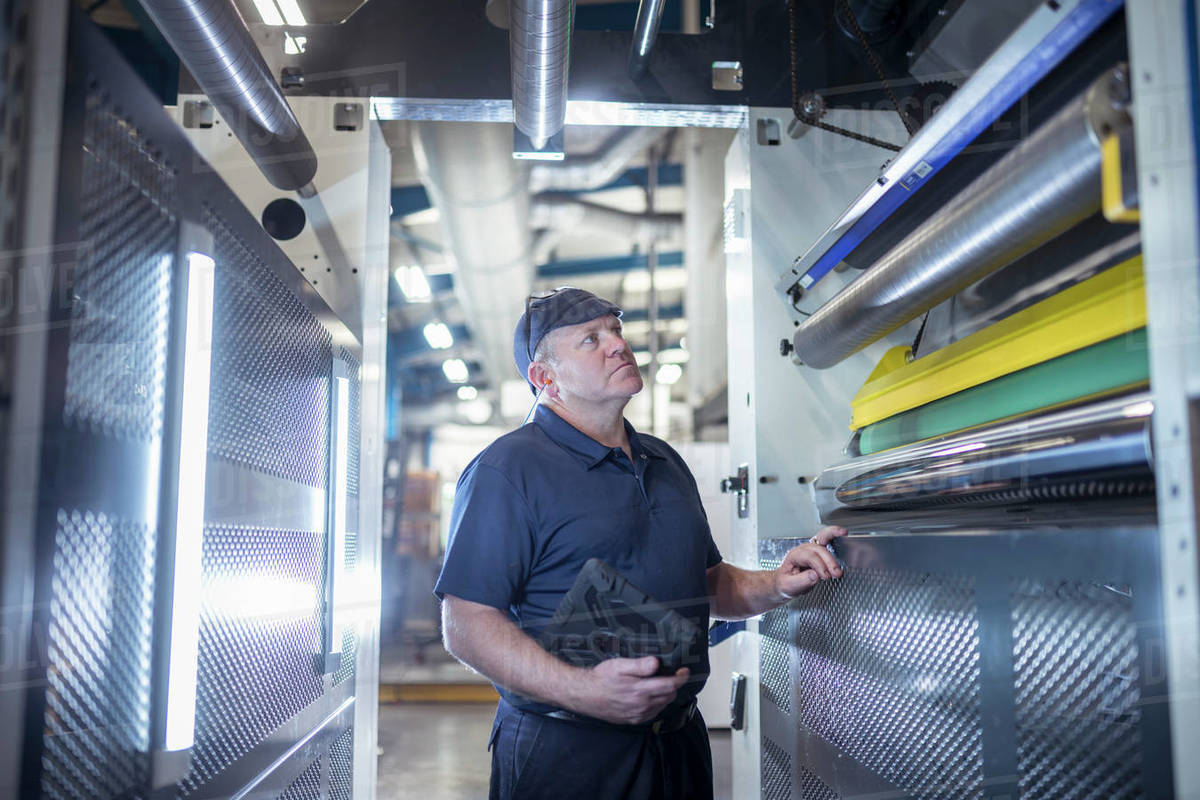 Worker inspecting interior of printing machine in print factory Royalty-free stock photo