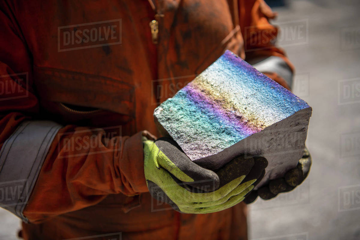 Worker holding fractured block of titanium alloy with coloured iridescence in titanium recycling plant Royalty-free stock photo