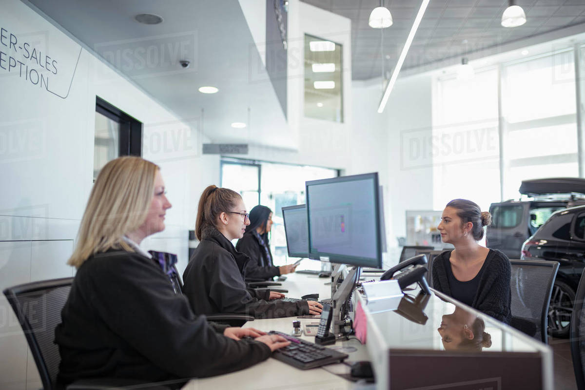 Female customer and staff at service desk in car dealership Royalty-free stock photo